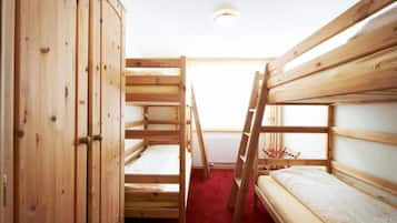 Une chambre avec des lits superposés en bois, une armoire et une échelle.