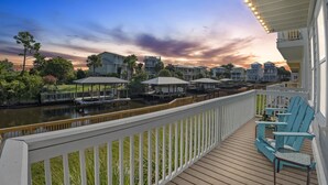 A waterfront deck with outdoor seating, a view of the water, and a sunset sky. - Beach Haven, Game Room, Arcades (Mexico Beach)