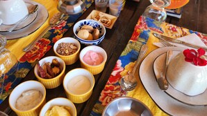 Una mesa dispuesta con diversos platos, incluyendo un postre con una flor encima, tazones con diferentes comidas y un vaso de un líquido marrón.