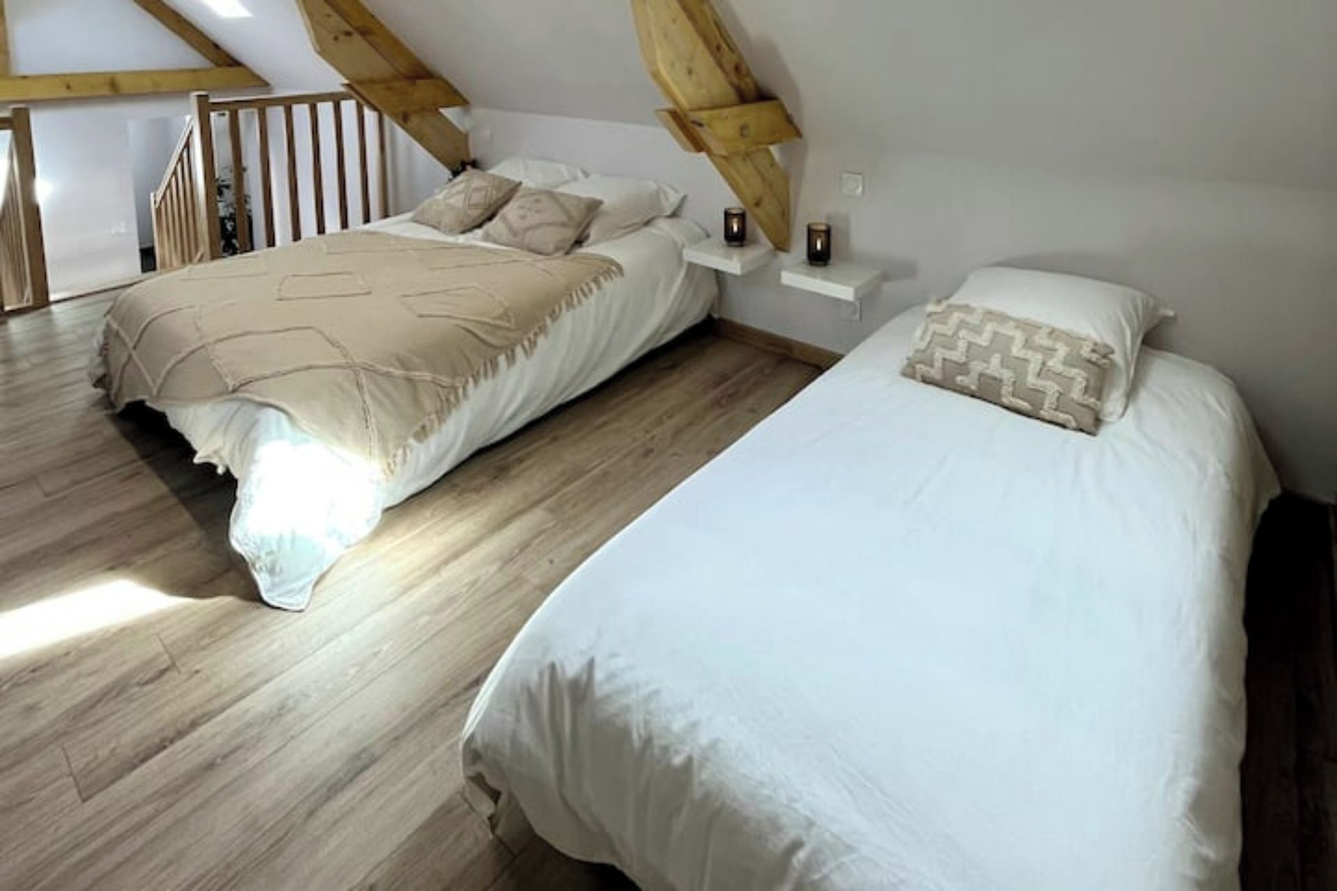 A bedroom with two beds, wooden flooring, and a sloped ceiling.