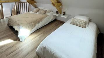 A bedroom with two beds, wooden flooring, and a sloped ceiling.