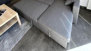 Un salon moderne avec un canapé d’angle gris, un escalier en bois et une petite table basse en bois.