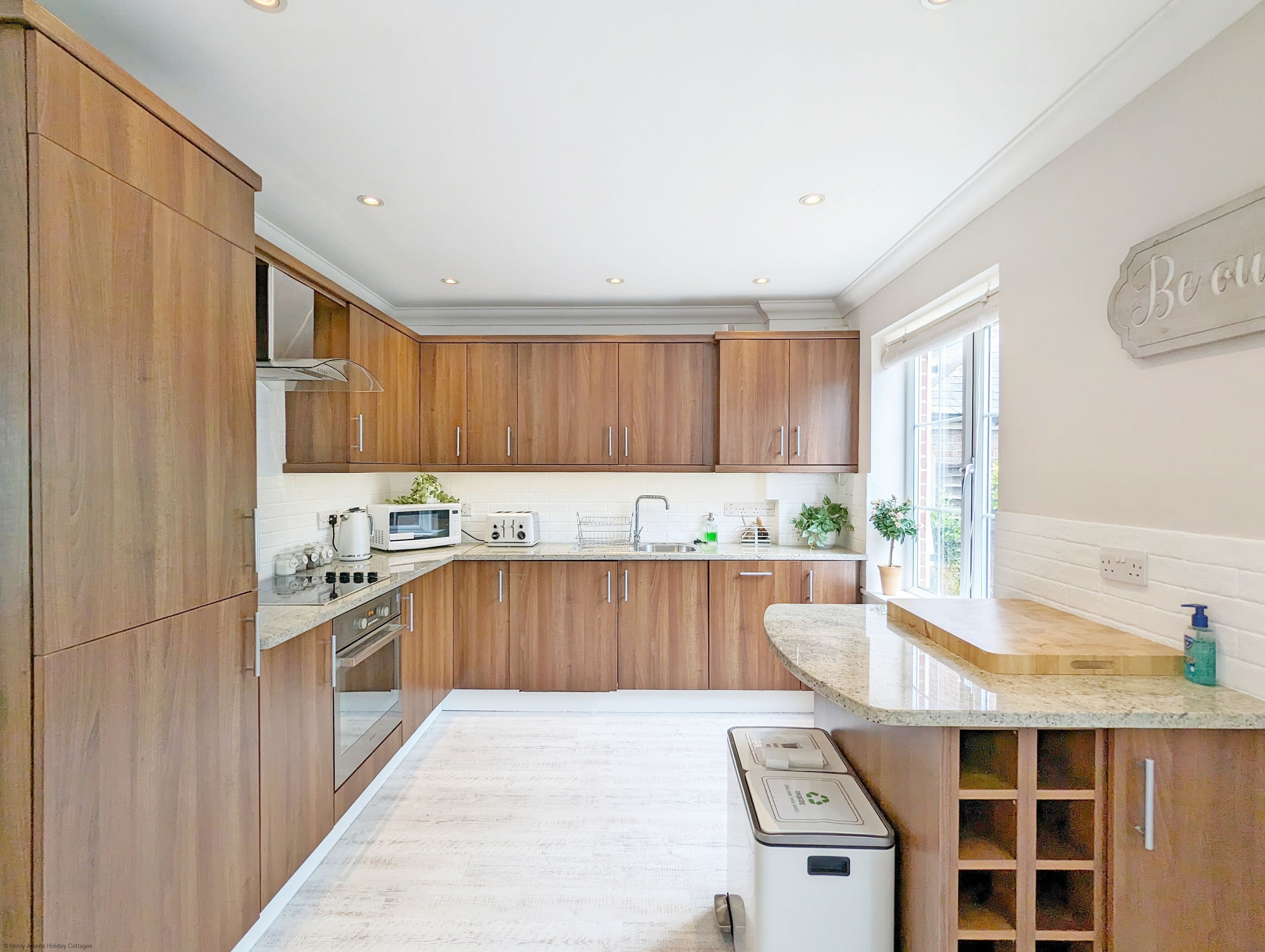 A modern kitchen with wooden cabinets, a built-in oven, a microwave, and a sink.