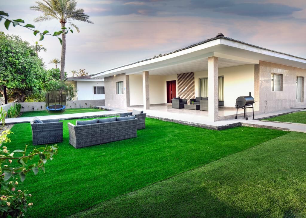 Une maison moderne dotée d’un patio couvert, d’une pelouse bien entretenue et de mobilier d’extérieur.