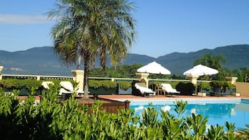 Una piscina cubierta, una piscina al aire libre, tumbonas