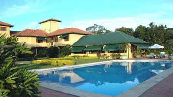 Alberca techada, alberca al aire libre y camastros