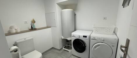 Ein kleines Badezimmer mit Toilette, Waschmaschine und Trockner.