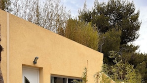 A modern building with a curved door, large sliding glass windows, and a patio area with outdoor seating. - Appartement T3 au RDC dans résidence sécurisé avec terrasse et barbecue (Martigues)