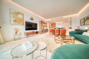 Un salon moderne avec un canapé vert, un téléviseur et un coin repas doté de chaises orange.