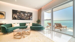 A modern living room with a green sofa, a coffee table, and a view of the ocean through large sliding glass doors. - Picturesque 3BR with Assistant Room at The One JBR by Deluxe Holiday Homes (Dubai)