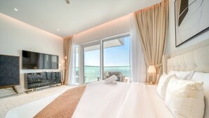 A hotel room with a large bed, a TV, a balcony with a view, and a modern decor style. - Picturesque 3BR with Assistant Room at The One JBR by Deluxe Holiday Homes (Dubai)