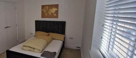 Un dormitorio con una cama, un mapa del mundo en la pared y una ventana con persianas.