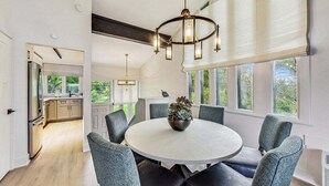 A modern dining area with a round table, grey upholstered chairs, and a decorative centerpiece. - Glass Vista: Modern 2BR Condo, Lake Views (Lake Geneva)