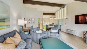 A spacious living room with a sofa, armchairs, a coffee table, and a TV. - Glass Vista: Modern 2BR Condo, Lake Views (Lake Geneva)