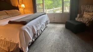A cozy bedroom with a bed, a chair, a window, and a ceiling fan. - Walk to Waterfalls!  Cozy All Seasons Highlands Cabin 6 min to Town (Highlands)