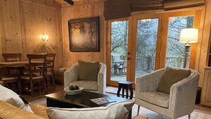 A cozy cabin interior with wooden walls, a dining area, two armchairs, and a sofa. - Walk to Waterfalls!  Cozy All Seasons Highlands Cabin 6 min to Town (Highlands)