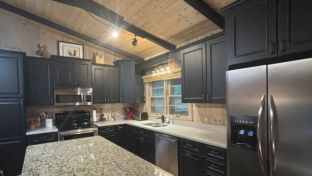 A modern kitchen with granite countertops, stainless steel appliances, and dark cabinetry. - Walk to Waterfalls!  Cozy All Seasons Highlands Cabin 6 min to Town (Highlands)