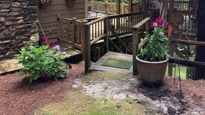 A rustic cabin with a stone wall and wooden deck, surrounded by a forest. - Walk to Waterfalls!  Cozy All Seasons Highlands Cabin 6 min to Town (Highlands)