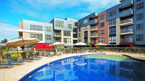 Um hotel moderno com piscina, área de estar ao ar livre e diversas varandas.