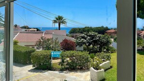Un quartier résidentiel offrant une vue dégagée sur l’océan, un panneau bleu indiquant un pâté de maisons et un palmier.