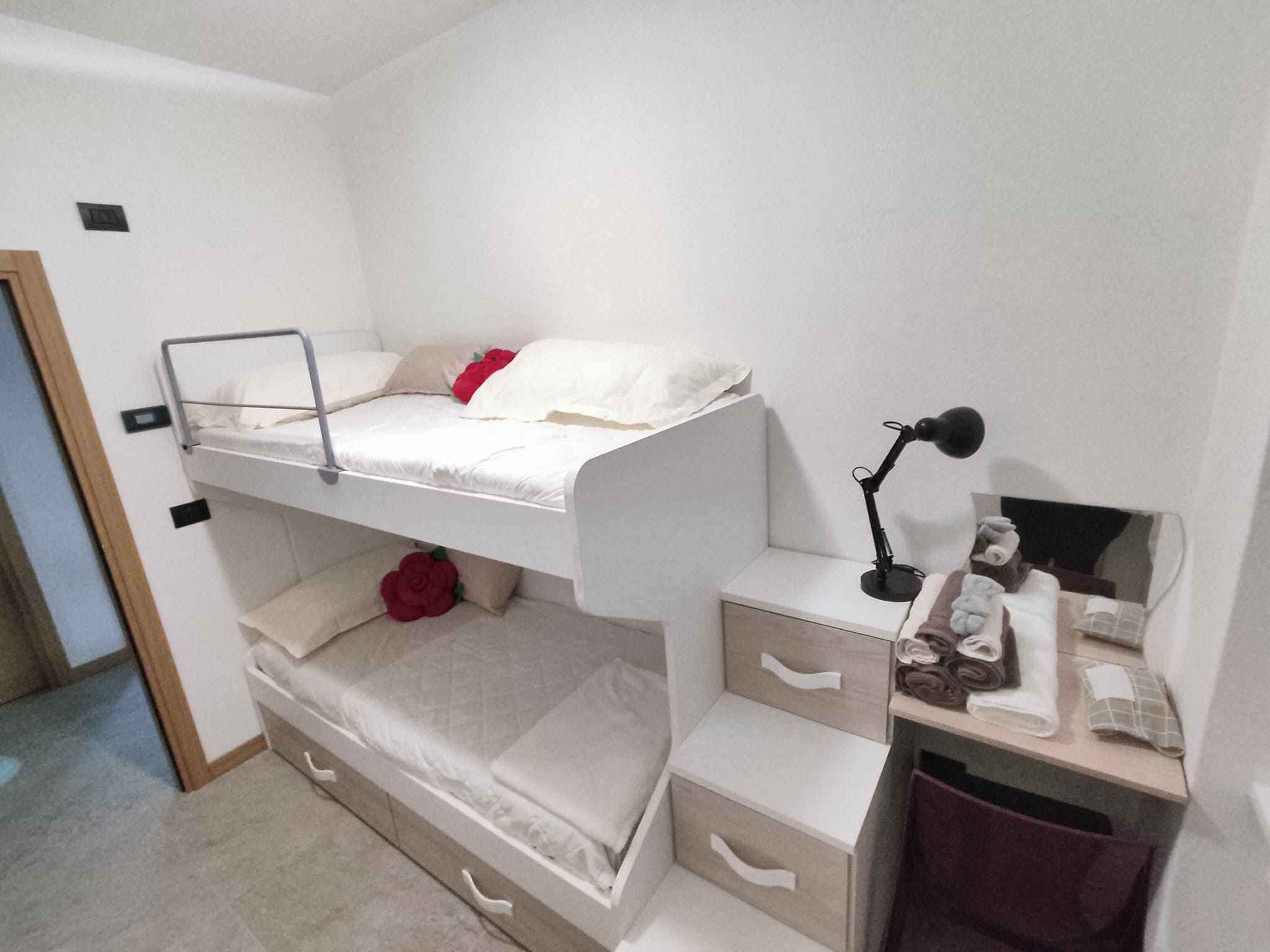 A bunk bed with storage drawers underneath, a desk with a lamp, and a mirror.