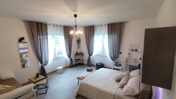 Un dormitorio con cama, escritorio, silla, cómoda, espejo y candelabro.
