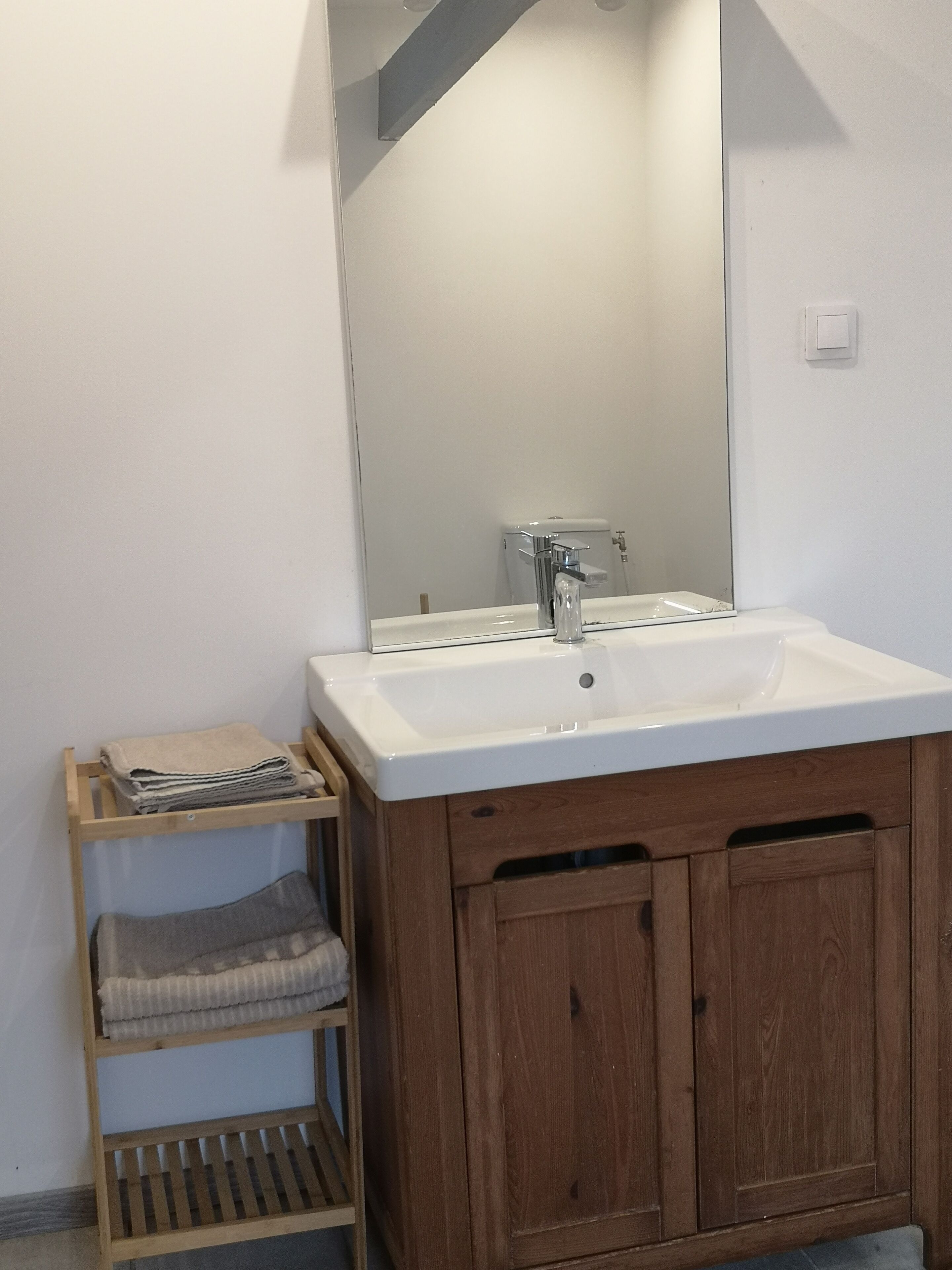 Une salle de bain avec un lavabo blanc, des meubles en bois et un miroir.