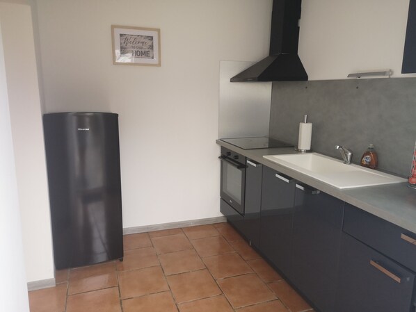 A modern kitchen with a black refrigerator, a stove, and a sink.