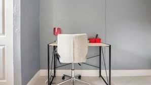 A corner room with a desk and chair, a red bag, and a white bag on the desk. - Cozy Studio in Miami (Miami)