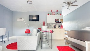 A compact living space with a sofa, a dining table, a TV, a kitchenette, and a ceiling fan. - Cozy Studio in Miami (Miami)