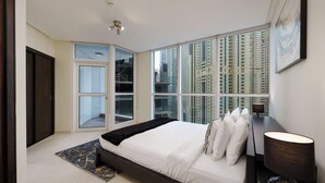 Una camera da letto moderna con un letto grande, vista su edifici alti, una porta e una finestra.