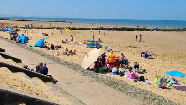 A beach with people sunbathing and swimming.