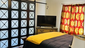Une chambre à coucher avec un lit, une télévision, un ventilateur de plafond et une fenêtre donnant sur un beau paysage.