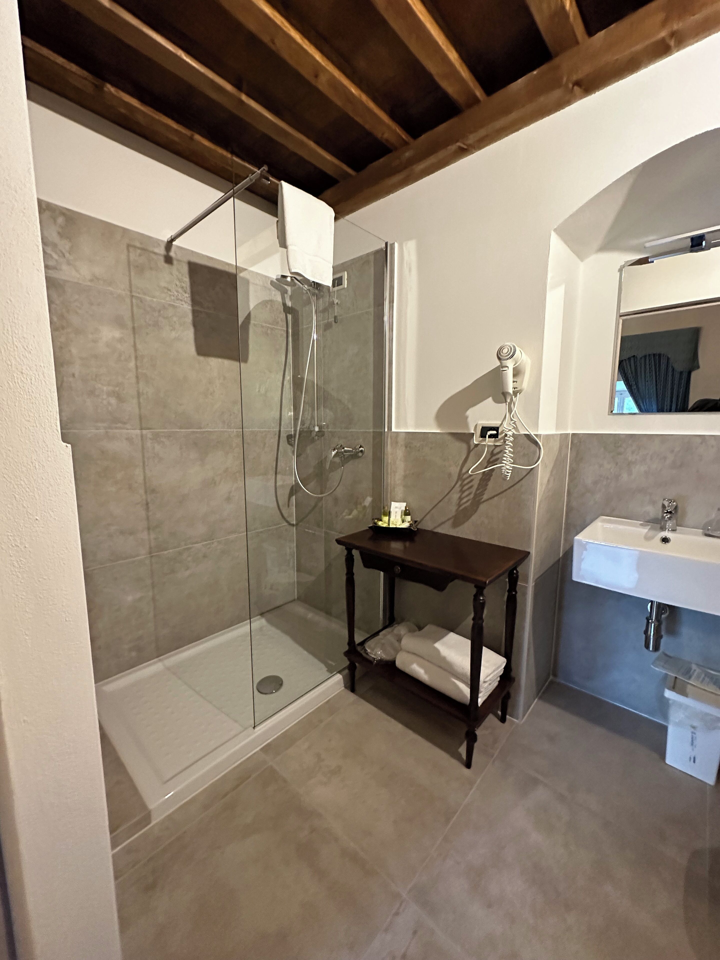 A bathroom with a glass-enclosed shower, a wooden vanity with a sink, and a mirror above the vanity.