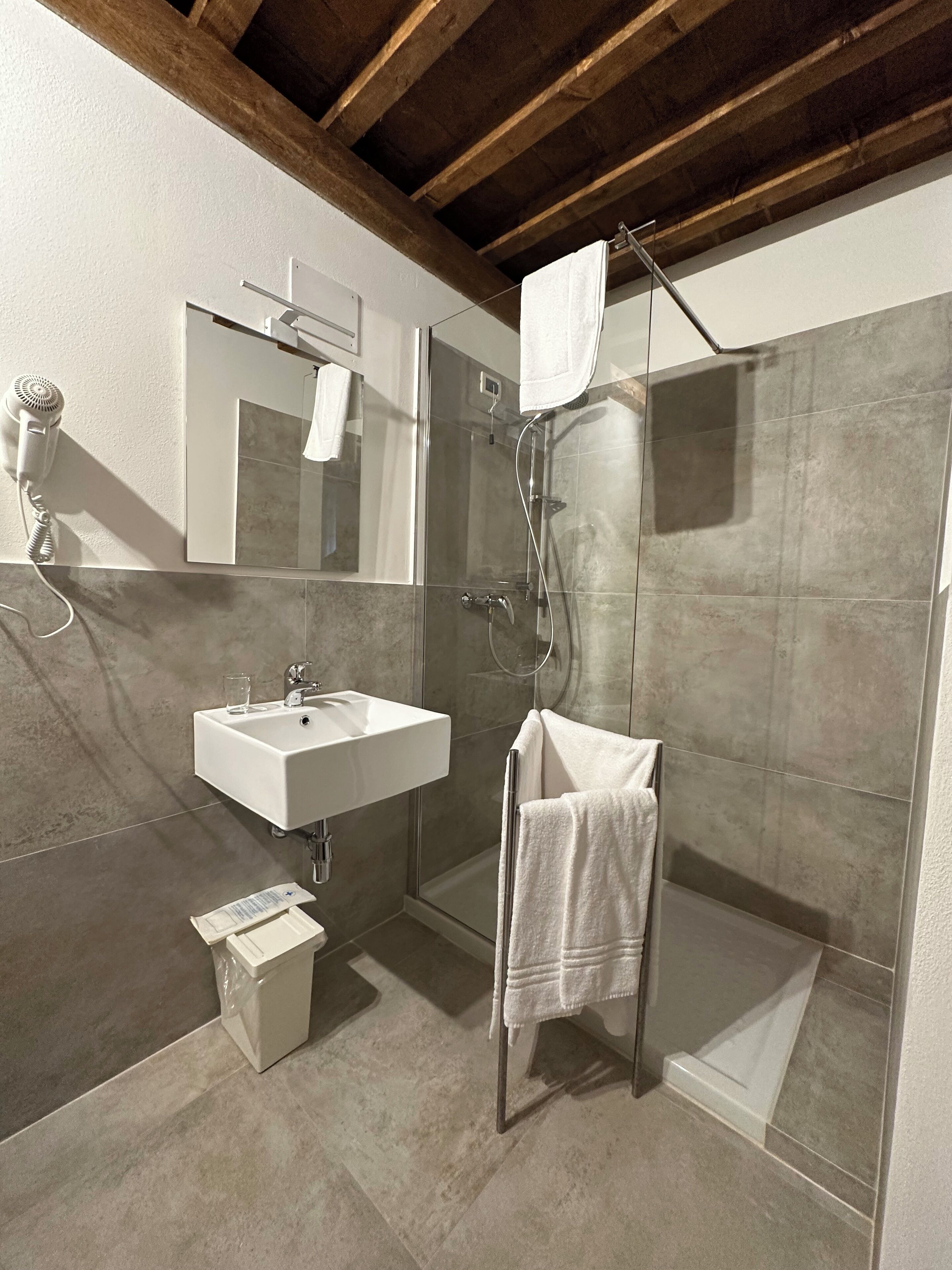 A modern bathroom with a glass-enclosed shower, a white sink, and a towel rack.