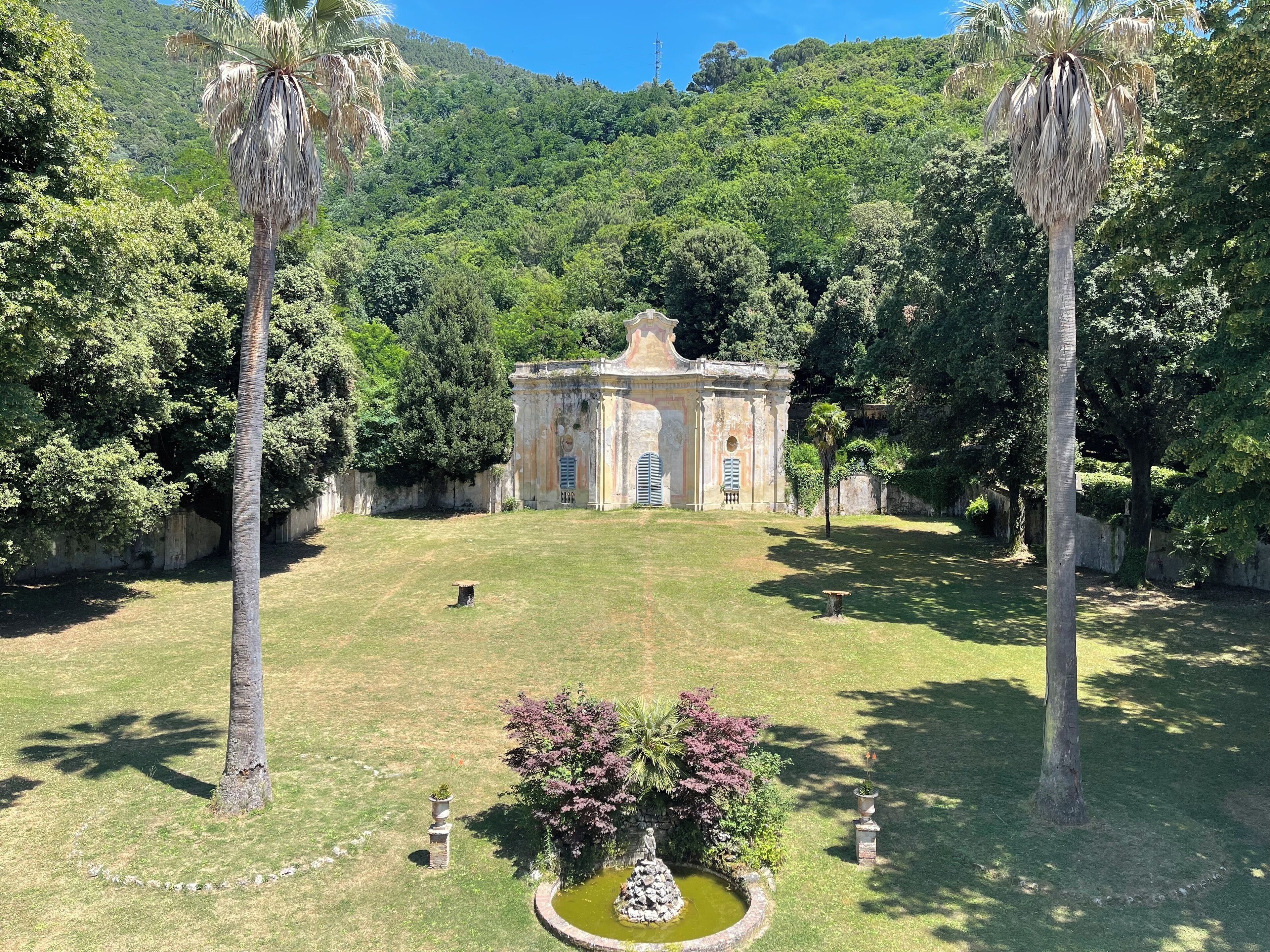 Un edificio histórico con un patio central, rodeado de abundante vegetación y palmeras.