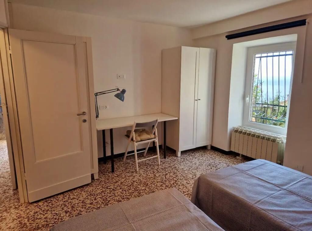 Ein Schlafzimmer mit Bett, Schreibtisch, Stuhl, Kleiderschrank und einem Fenster mit Aussicht.