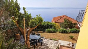 A patio with a table and chairs, a stone pathway, and a view of the sea. - Panoramic garden on the sea, a corner of Liguria (Sant'Andrea di Rovereto)