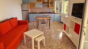 A compact living space with a kitchenette, a dining area with a table and chairs, and a sofa. - Panoramic garden on the sea, a corner of Liguria (Sant'Andrea di Rovereto)