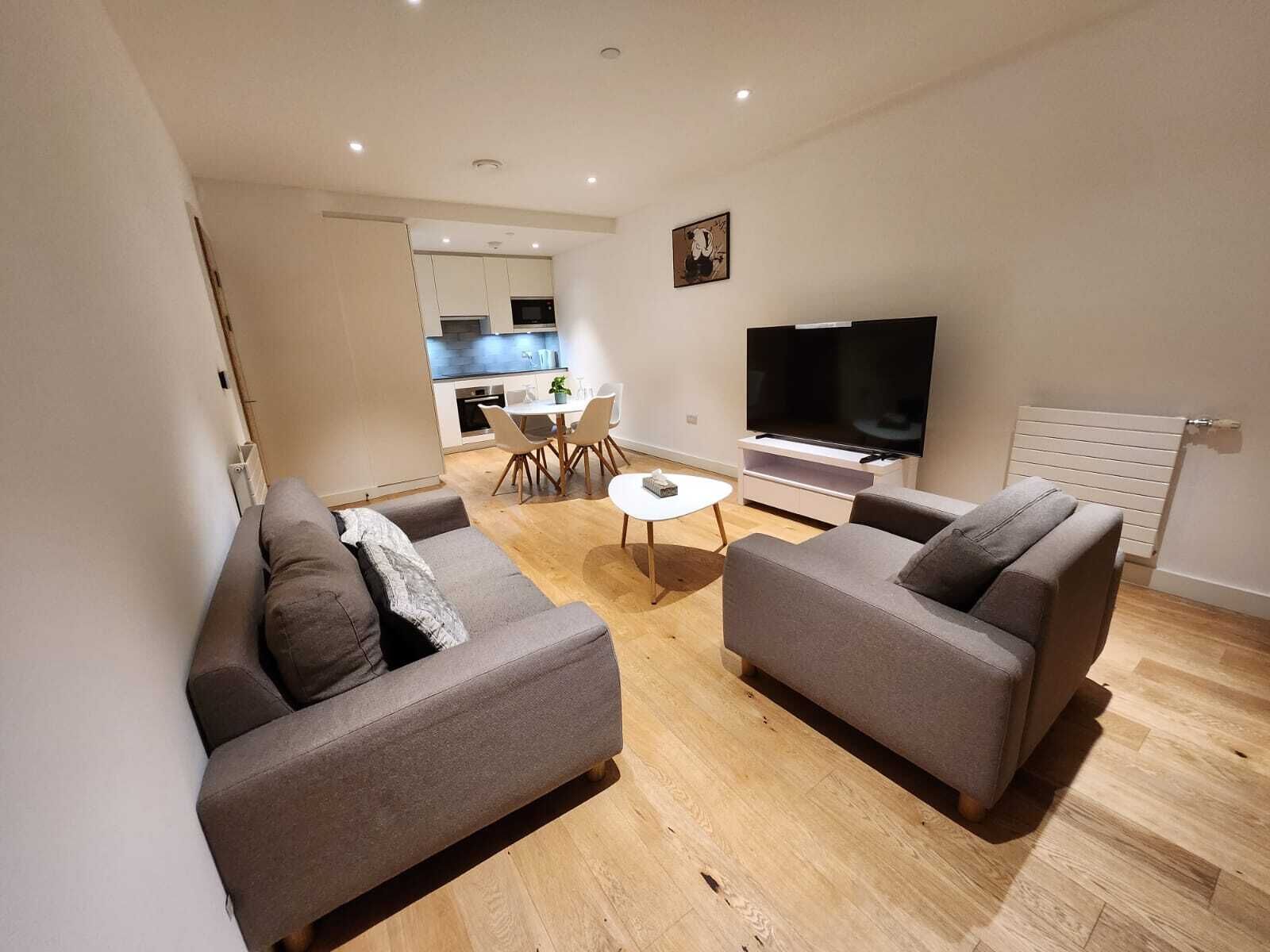 A modern living room with two grey sofas, a coffee table, and a TV.