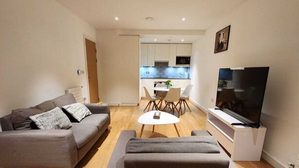Una sala de estar moderna con un sofá gris, una mesa de centro y un televisor.