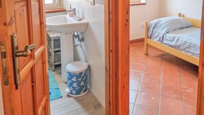 A room with a wooden door, a sink, a toilet, and a bed.