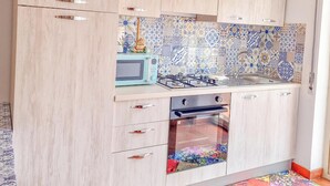 A kitchen with light wood cabinets, a tiled backsplash, a microwave, a gas stove, and an oven.