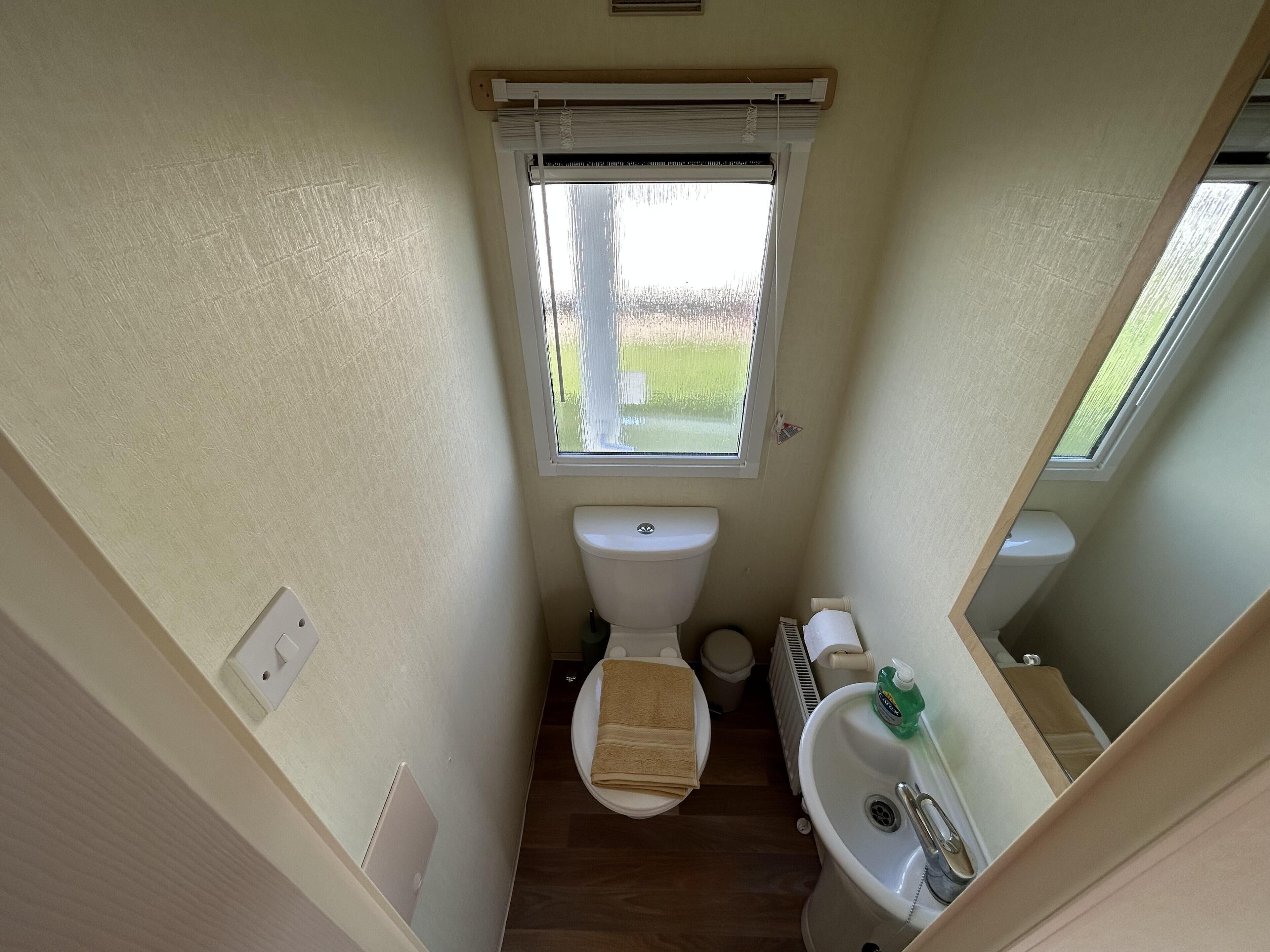 A compact bathroom with a toilet, sink, and window.