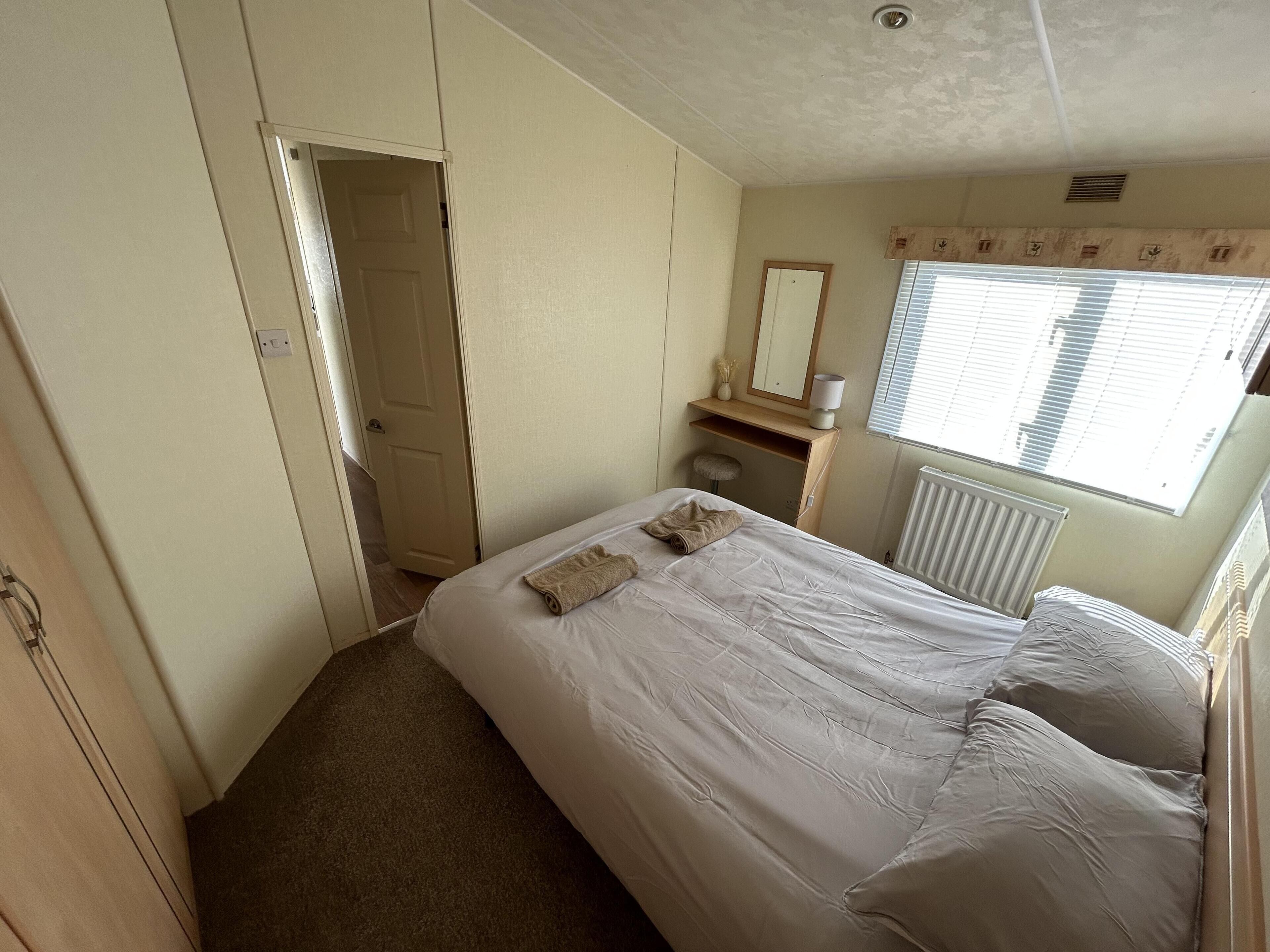 Une chambre à coucher avec un lit, une commode, un miroir et une fenêtre avec des stores.