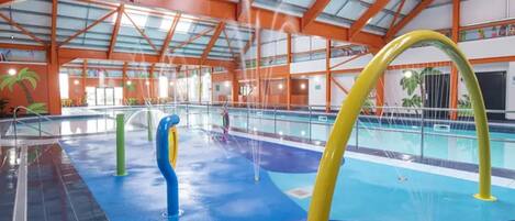 An indoor swimming pool with a high ceiling and orange structural beams.