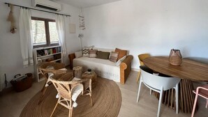 Un salon chaleureux avec un canapé, des fauteuils en osier, une table à manger et un ventilateur de plafond.