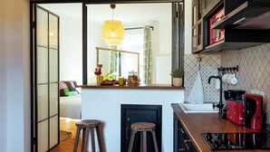 Una cucina moderna con un piano di lavoro in legno, sgabelli e vista sull'area soggiorno.