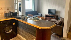A compact living space with a kitchenette, a sofa, a television, and a dining area.