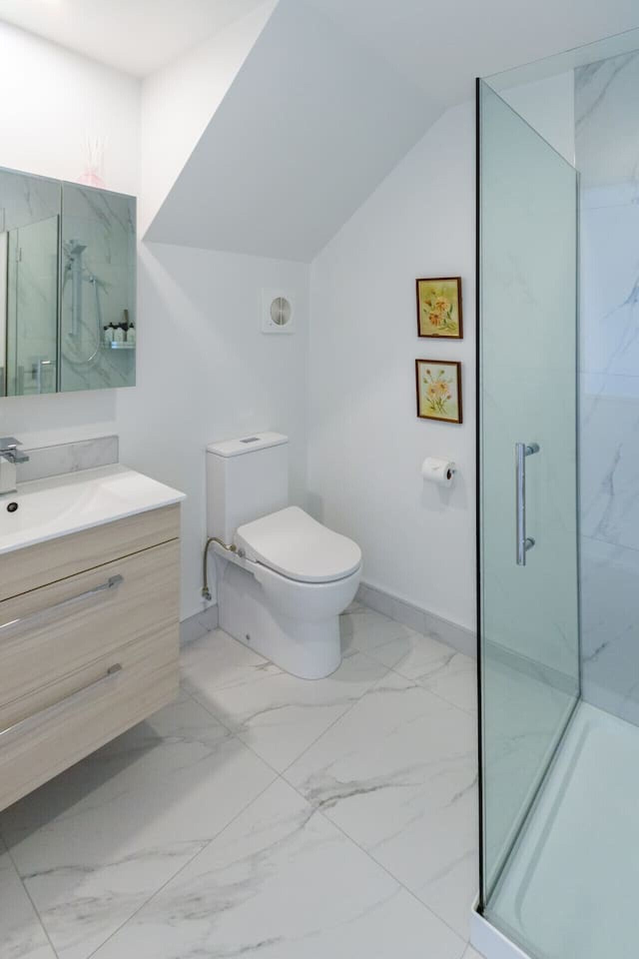 Ein modernes Badezimmer mit einer Duschkabine aus Glas, einer weißen Toilette und einem Boden mit Marmorfliesen.